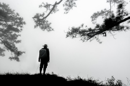 Silhouette of backpacker standing on the mountain and watching over misty and foggy morning in Phu Kradueng National Park , Thailand.の写真素材