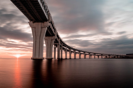 Long exposure view of the Western Diameter Bridge in St. Petersburg at sunset, with smooth water and...
