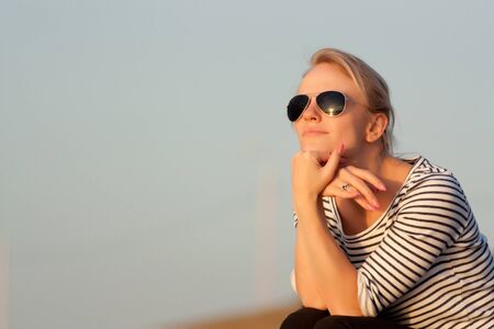 A beautiful girl is sitting  and enjoying the sunsetの写真素材