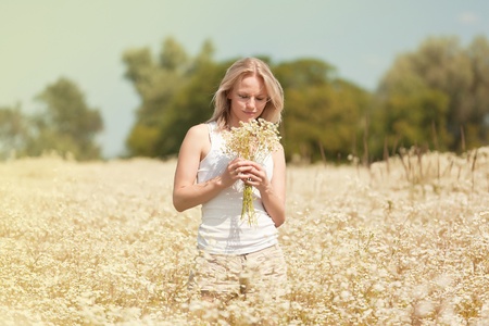 A beautiful young blond girl in a field with white daisiesの写真素材