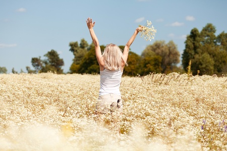 A beautiful young blond girl in a field with white daisiesの写真素材