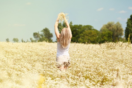 A beautiful young blond girl in a field with white daisiesの写真素材