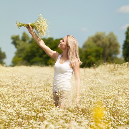 A beautiful young blond girl in a field with white daisiesの写真素材