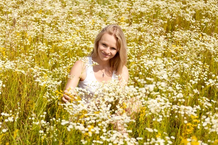 A beautiful young blond girl in a field with white daisiesの写真素材