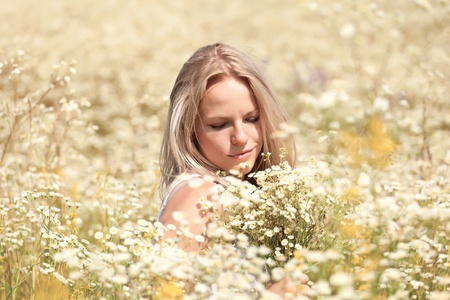 A beautiful young blond girl in a field with white daisiesの写真素材