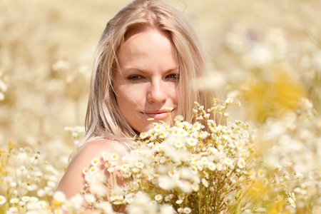 A beautiful young blond girl in a field with white daisiesの写真素材