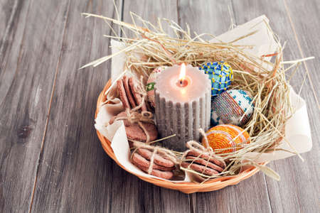 Easter eggs, candles and cookies in a basketの写真素材