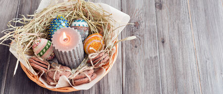 Easter eggs, candles and cookies in a basketの写真素材