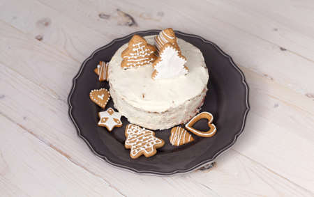 White cake with cookies in the shape of Christmas trees on a wooden white backgroundの写真素材