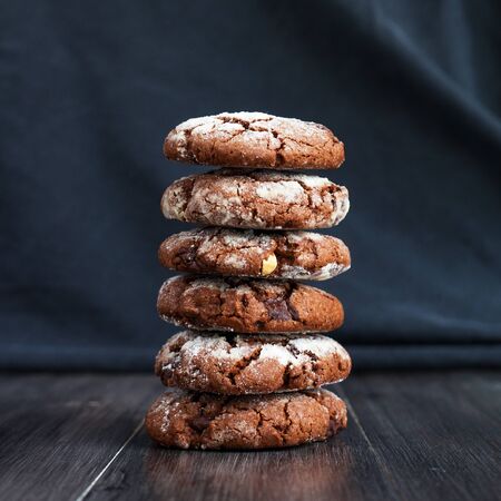 Chocolate cookies, sprinkle with powdered sugar. Folded on each other. Cookies on a dark backgroundの写真素材