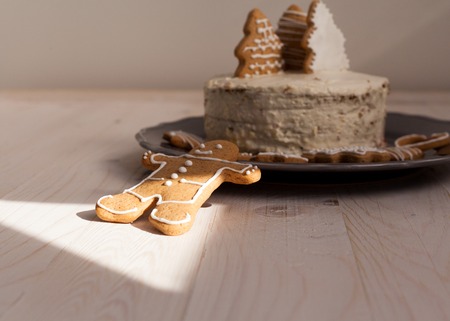 White cake with cookies in the shape of Christmas trees on a wooden white background