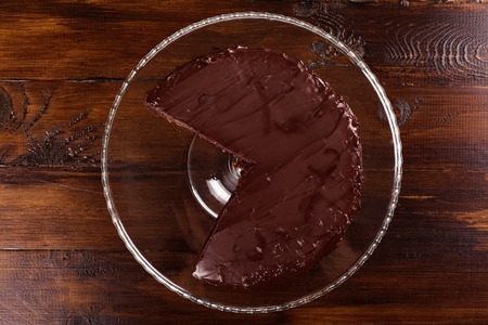 Sacher chocolate cake in a cut on a glass stand on a dark background. Top view.の写真素材