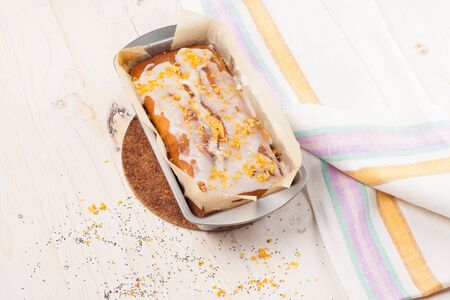 Lemon cake with poppy seeds drizzled with white icing on a wooden background. Top view.の写真素材