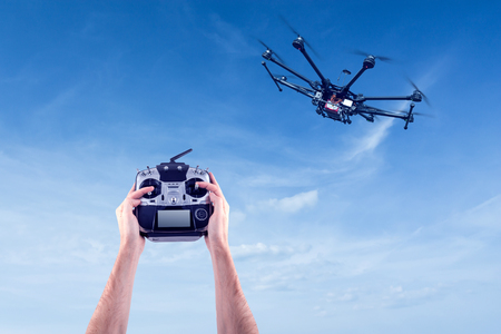 Hands of a man with a radio control drone on a background of beautiful blue sky