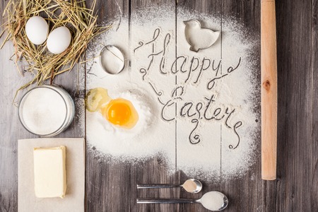 Ingredients for the dough for Easter. Eggs, flour, butter, sugar and kitchen tools on a dark wooden...