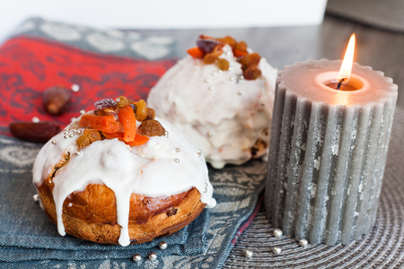 Rich Easter cake with dried fruits and a burning candle on a gray background.の写真素材