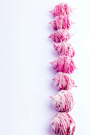 Delicious homemade sweet pink marshmallow with blackcurrant, dusted with icing sugar on a white background. Top view.の写真素材