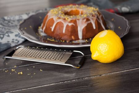 Delicious fresh rustic lemon cake covered with icing with lemon zest on top.の写真素材