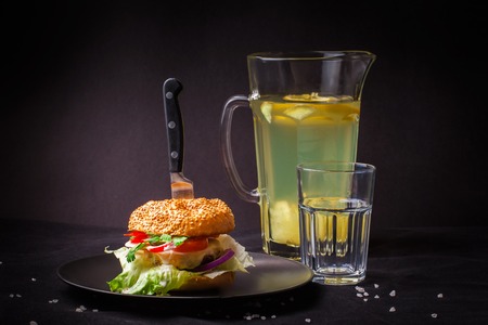 Homemade delicious juicy burger with fresh ginger lemonade on a dark background.の写真素材