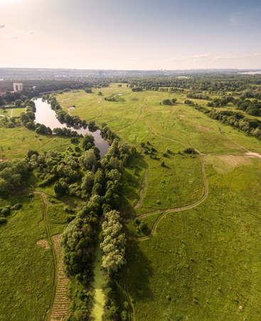 Beautiful sunset on a lush green field with river in the background. Rural landscape. Aerial view.の写真素材