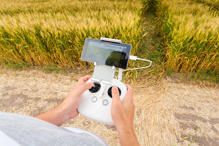 Demonstration of unmanned copter. Man controls quadrocopter flight. Flying the copter over a field...