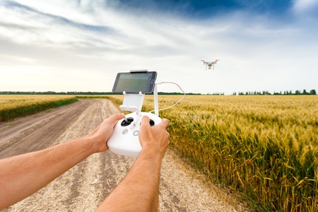 Demonstration of unmanned copter. Man controls quadrocopter flight. Flying the copter over a field...