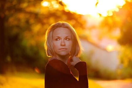 Trendy girl at sunset in spring landscape background. Spring time. Sunset in the park.の写真素材