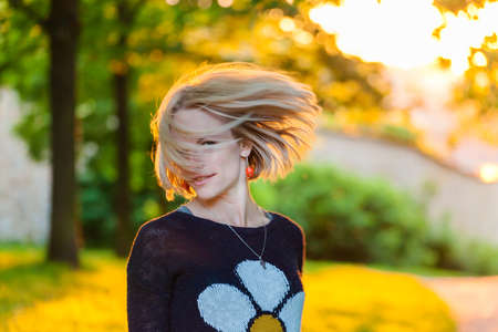 Trendy girl at sunset in spring landscape background. Spring time. Sunset in the park.の写真素材