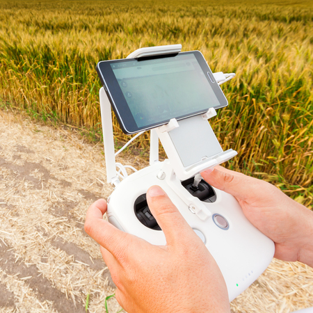 Demonstration of unmanned copter. Man controls quadrocopter flight. Flying the copter over a field...