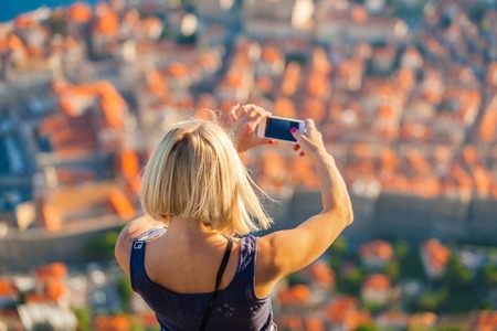 Female traveler make a panoramic photo of the old city of Dubrovnik from the mountain, Croatia.の写真素材