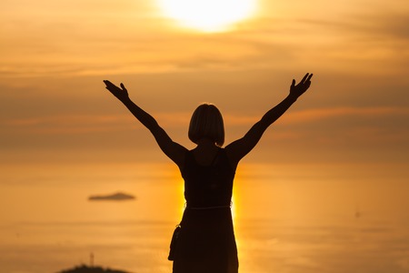 Female tourist standing on the background of Bay at sunset. Misty layers of islands. Sunset in...