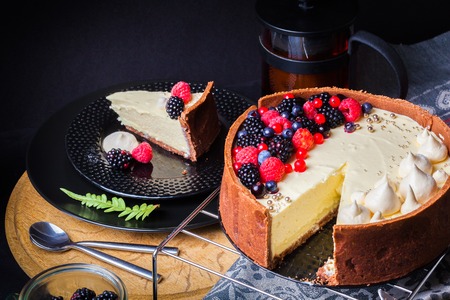 Cake with white chocolate mousse, lime confit, fruits and berries on top as decoration. The process of preparing a tea party with homemade fresh cake.の写真素材