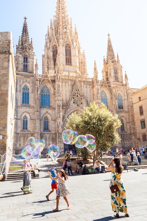 BARCELONA, SPAIN - AUGUST 25, 2016: Children playing with soap bubbles on the background of Cathedral of the Holy Cross and Saint Eulalia in Barcelona, Spain.のeditorial素材