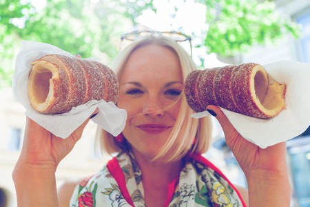 Young female tourist with traditional czech dessert called trdelnik in Prague. Czech Republic. Outdoorの写真素材