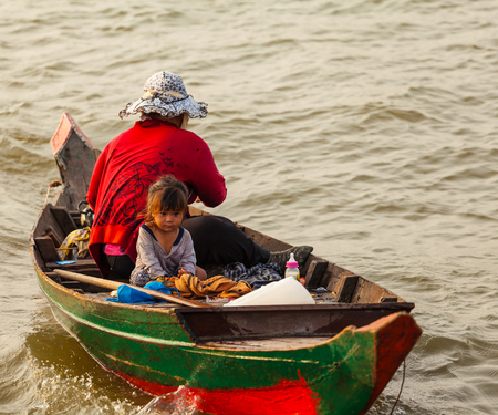 Tonle Sap Lake Siem Reap, Cambodia - OCTOBER 13, 2012: Asian woman floating on a boat with beautiful little girl. The life of the local residentsのeditorial素材