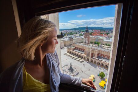 Female traveler standing on the tower of the church of St. Mary and looks to the Main Market Square in Krakow. Polandの写真素材