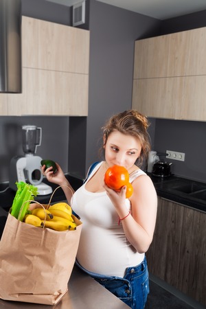 Pregnant woman with a bag of fresh fruit and vegetablesの写真素材