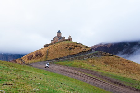 Gergeti Trinity Church Or Tsminda Sameba in the morning mist near village Stepantsminda, Georgia....