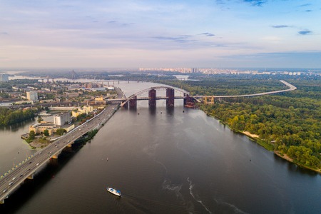 Panoramic view of a modern city with a river, unfinished bridge and park part of the cityの写真素材
