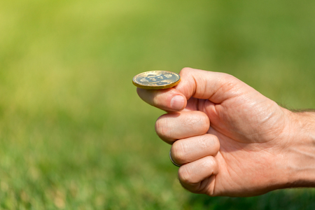 A mans hand throws a gold coin bitcoinの写真素材