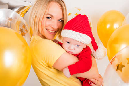 Newborn baby with mom on the background of Christmas ballsの写真素材
