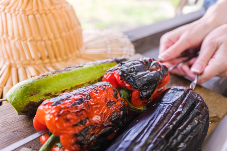 Grilled vegetable on a grill pan. Woman holding a skewer with grilled vegetables over a wooden plankの写真素材