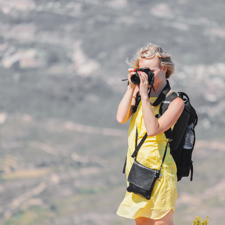 Female traveler with a backpack on her back enjoying the views from the mountains of Montserrat in Spain and makes a photoの写真素材