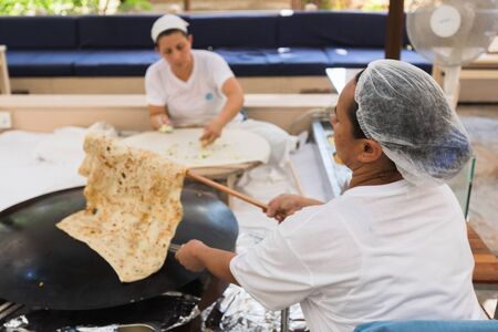 Two Turkish women are sitting and cooking Turkish Gozleme.のeditorial素材