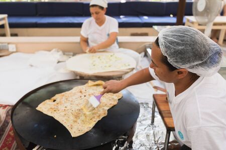 Two Turkish women are sitting and cooking Turkish Gozleme.のeditorial素材