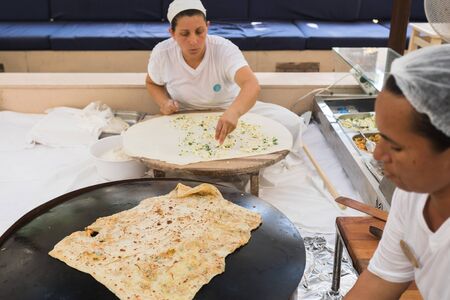 Two Turkish women are sitting and cooking Turkish Gozleme.のeditorial素材