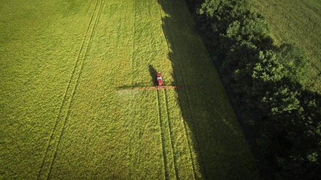 Agricultural machinery in the field. Tractor with a sprayer. Aerial view