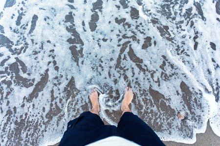 Blue waves in the sand with male feet