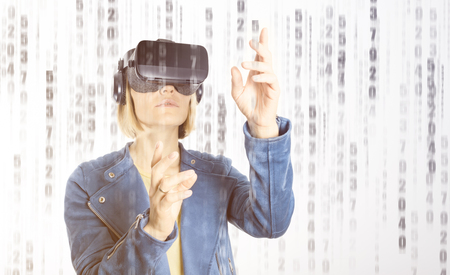 A young woman is wearing virtual reality glasses and reaching for something with his handsの写真素材