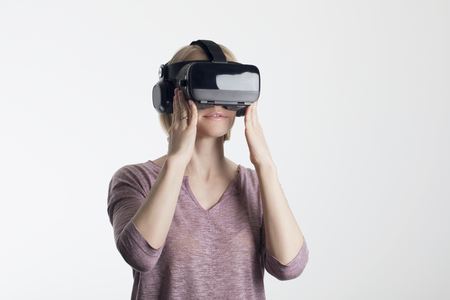 A young woman is wearing virtual reality glasses and reaching for something with his hands